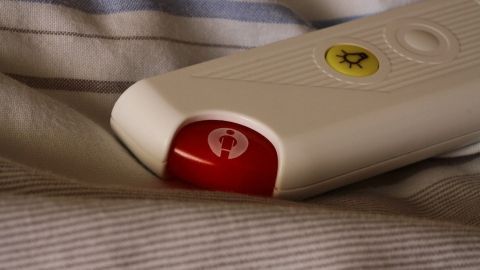 Ein roter Notfallknopf liegt auf einem Bett, um Patienten im Krankenhaus schnelle Hilfe zu ermöglichen.