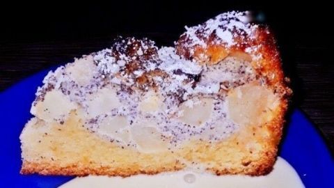 Ein Stück Apfel-Mohn-Quarkkuchen liegt auf einem blauen Teller und wird von einer cremigen Sauce umgeben.