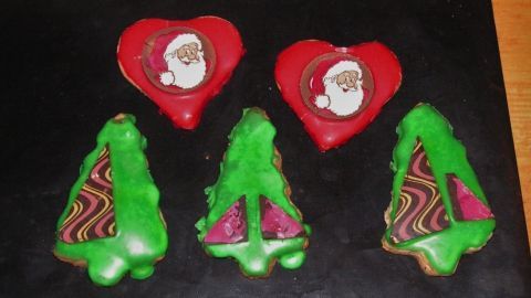 Bunte Weihnachtskekse in Form von Herzen und Bäumen liegen auf einem schwarzen Hintergrund, bereit zum Verzehr.