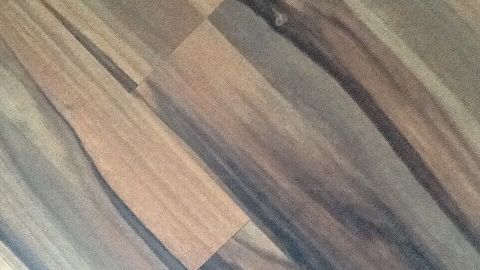 Dunkles Laminat zeigt eine strukturierte Oberfläche mit verschiedenen braunen und grauen Holzmaserungen in einem eleganten Design.