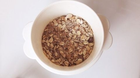 Eine Schüssel mit Müsli steht auf einem Tisch, gefüllt mit Haferflocken und Schokoladenstückchen, bereit zum Genießen.