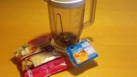Ein Mixer steht auf einem Tisch, umgeben von Tüten mit Zitronat und Orangeat, bereit zum Zerkleinern.