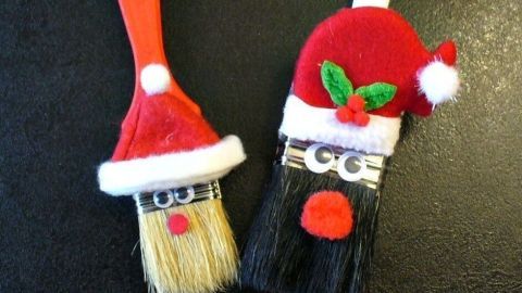Zwei Malerpinsel sind kreativ zu Nikolausfiguren dekoriert. Sie tragen Weihnachtsmützen und einen roten Bart im festlichen Kontext.