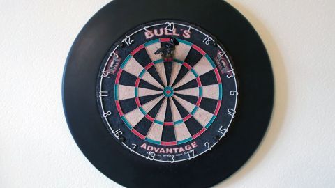 Ein Dartscheibe hängt an der Wand, bereit für ein Spiel, und zeigt das typische schwarz-weiße Feld mit dem Zielbereich.