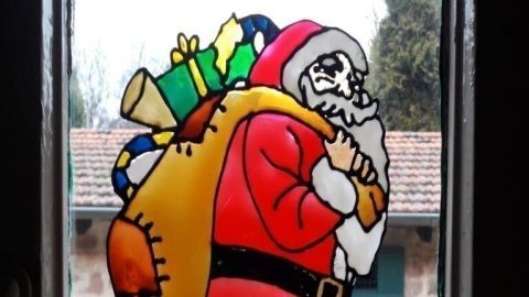 Ein bunter Weihnachtsmann mit Geschenken im Sack hängt an einem Fenster und sorgt für festliche Stimmung im Raum.