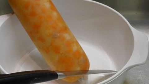 Ein Schlauchbeutel mit frischer Suppe steht in einer Schüssel, während ein Messer zum Öffnen bereitliegt.