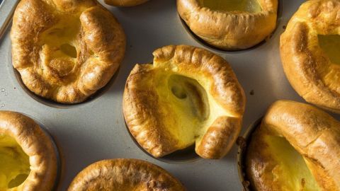 Gebackene Beilagen liegen warm in einer Backform, gleichmäßig gebräunt mit goldenem, aufgegangenen Teig.