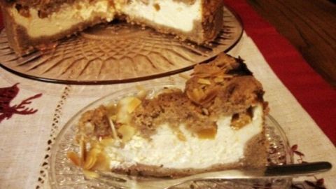 Eine festliche Quark-Schmand-Torte liegt auf einem Glasschalen, während ein Stück auf einem Teller serviert wird.