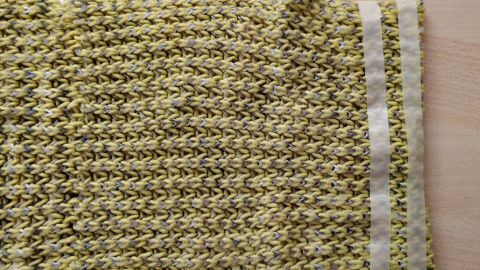 Ein gestrickter Loop liegt auf einem Tisch und zeigt eine gut erkennbare Struktur mit einem schlichten, gemusterten Design.