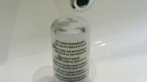 Eine Flasche steht im Waschbecken und könnte beim Colorieren der Haare benutzt werden, um Farbe aufzutragen.
