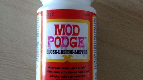Ein Behälter mit Mod Podge steht auf einem hölzernen Tisch, bereit für kreative Bastelprojekte. Der Alleskönner unter den Klebern!