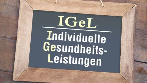 Ein Holzrahmen hält eine Tafel mit der Aufschrift "IGeL Individuelle Gesundheits-Leistungen", die über Gesundheitsleistungen informiert.