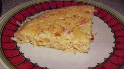 Eine Spaghetti-Frittata liegt auf einem bunten Teller und wird serviert, nachdem sie gebacken und leicht goldbraun geworden ist.
