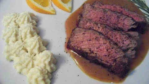 Saftiges Roastbeef vom Limousin Rind, in Scheiben geschnitten, serviert mit cremigem Kartoffelpüree und Orangenscheiben.