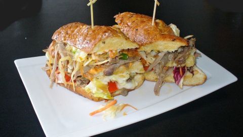 Ein Männersandwich mit zartem, gefülltem Geplänkel auf einem weißen Teller, perfekt angerichtet und serviert.