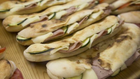 Knuspriges Fladenbrot liegt auf einem Holzbrett, gefüllt mit frischem Gemüse und Aufschnitt, appetitlich angerichtet.