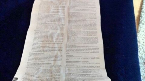 Ein langer, gefalteter Beipackzettel liegt auf einem blauen Untergrund und enthält dichte, kleine Schrift.