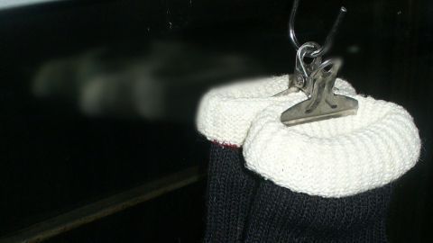Ofen- und Silikonhandschuhe hängen an einem Haken in der Küche, bereit für den Einsatz beim Kochen oder Backen.