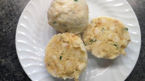 Semmelknödel liegen auf einem weißen Teller, zwei aufgeschnitten, präsentieren eine weiche, füllige Textur.