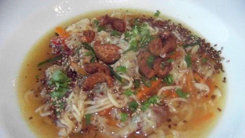 In einer weißen Schüssel liegt eine leckere Chinakohlsuppe, die mit Entenbrust, Gemüse und knusprigen Einlagen garniert ist.