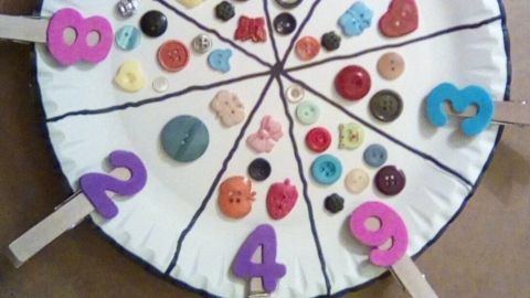 Eine bunte Zähl-Schablone zeigt Zahlen und verschiedene Knöpfe, die Kinder zum spielerischen Zählen anregen.