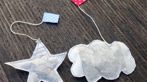 Zwei originelle Teebeutel in Form eines Sterns und einer Wolke liegen auf einem Holztisch, bereit für eine DIY-Teemischung.
