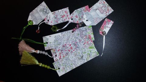 Bunte Lesezeichen und Geschenkanhänger aus Verpackungen liegen verstreut auf einem dunklen Untergrund, bereit zur Verwendung.