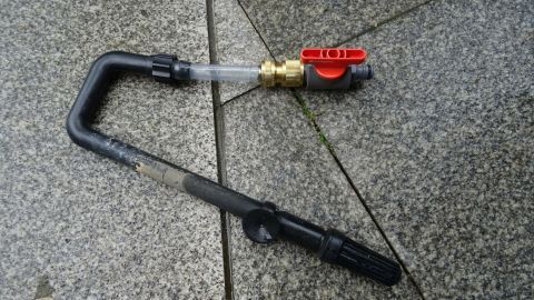 Ein Wasserwechselgerät liegt auf einem grauen Untergrund, bereit für die Verwendung im Aquarium zur Wasserentnahme.