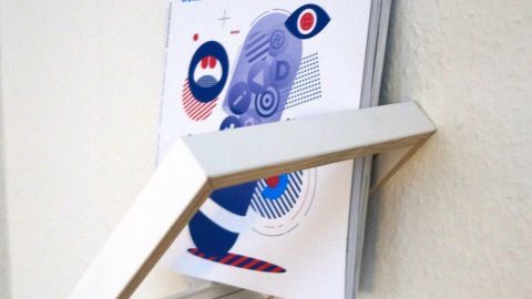 Ein stilvolles Zeitschriftenregal aus Bilderrahmen hält die Zeitschrift "novum" an der Wand, modern und kreativ platziert.