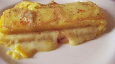 Eine goldene Polenta mit geschmolzener Fontina liegt auf einem weißen Teller und strahlt Wärme und Genuss aus.