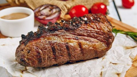 Saftiges Flanksteak liegt auf Backpapier, umgeben von Dips und Gemüse, bereit zum Genießen.