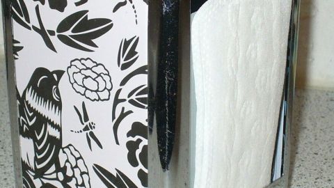 Ein eleganter Behälter mit floralem Design bewahrt Slipeinlagen dezent auf und steht auf einer glatten Oberfläche.