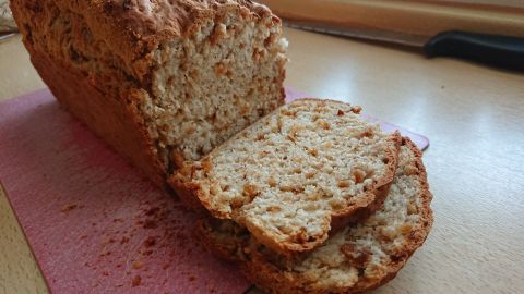 Ein frisch gebackenes Zwiebelbrot liegt auf einem Tisch, einige Scheiben sind bereits abgeschnitten und auf einer Unterlage platziert.