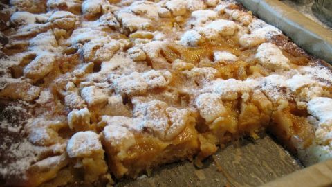 Der Kuchen hat eine goldene, luftige Oberfläche mit stückiger Ananas und Puderzucker, serviert auf einem Blech.