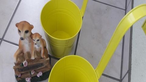 Zwei leuchtend gelbe Blumenkästen stehen daneben, während eine Dekoration von zwei sitzenden Welpen im Hintergrund platziert ist.
