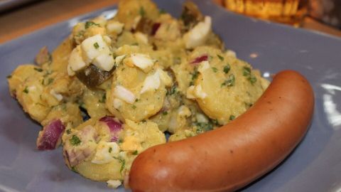 Der Teller enthält salzarmes Würzgericht mit Kloß und einer Wurst, appetitlich angerichtet in einem gemütlichen Umfeld.