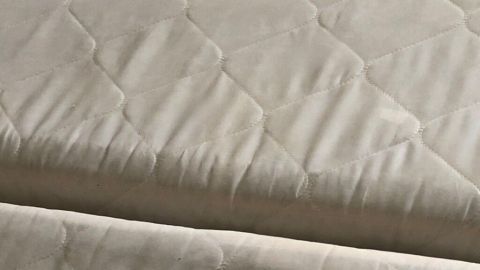 Eine helle Matratze liegt auf einem Bett, im Fokus steht die Textur, ideal zum Entfernen von Urinflecken.