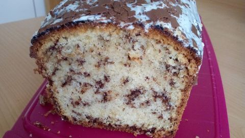 Ein saftiger Schokoraspelkuchen liegt auf einem pinken Schneidebrett, umgeben von einer hellen Küchenumgebung.