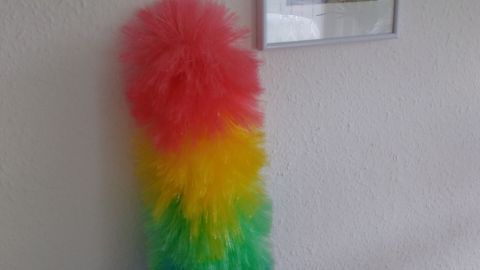 Bunter Staubwedel steht an einer Wand und wartet darauf, Staub zu wischen, um für saubere und ordentliche Räume zu sorgen.