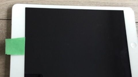 Ein Tablet liegt auf einem Holztisch, es hat ein grünes Klebeband auf der oberen Kante zum Schutz vor Kamera-Überwachung.