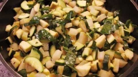 In einer Pfanne wird eine bunte Mischung aus Zucchini, Kohlrabi und Äpfeln gedünstet, die frisch und gesund aussieht.