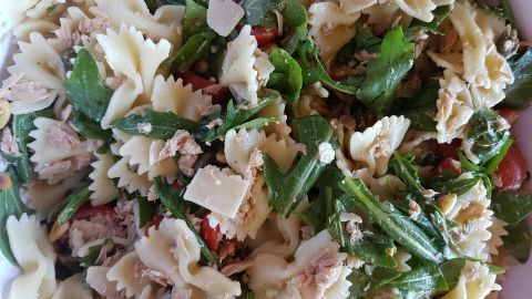 Ein bunten Nudelsalat mit Thunfisch und Rucola zeigt frische Zutaten in einer Schüssel, bereit zum Servieren.