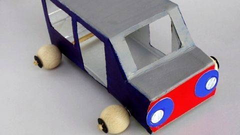 Ein bunter Bus aus Milchkarton steht auf einer Fläche und zeigt kreative Gestaltung mit Fenstern und Rädern.