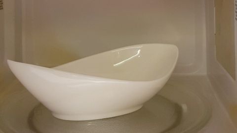 Eine schlichte, weiße Schüssel liegt in einer Mikrowelle und wird dort zum Erwärmen von Speisen genutzt.