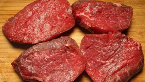 Rohes Fleisch liegt auf einem Holzbrett, was auf eine mögliche Zubereitung in einer Küche hinweist, wo frische Lebensmittel wichtig sind.