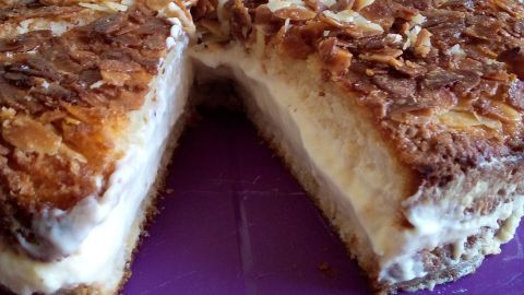 Ein Bienenstich mit Quark-Öl-Teig zeigt eine Torte mit einer goldbraunen, knusprigen Oberfläche und einer cremigen Füllung.