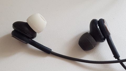 Weiße und schwarze Ohrhörer liegen nebeneinander, wobei die weiße Ohrmuschel deutlich links zu sehen ist.