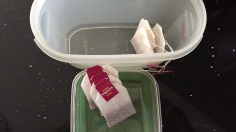 Plastikbehälter, gefüllt mit Teebeuteln, stehen auf einer Tischoberfläche in einer Küche zur Aromatisierung.