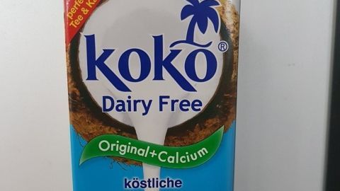 Ein Karton mit "koko Dairy Free" Pflanzenmilch steht auf einer Arbeitsfläche und zeigt den Inhalt, der gerade ausgegossen wird.