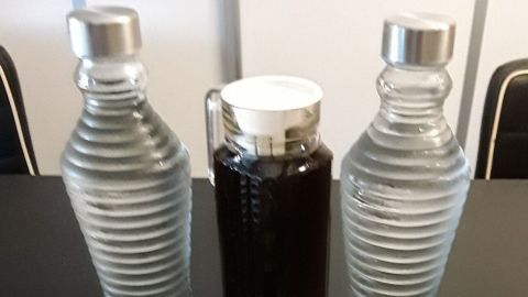 Karaffen mit Wasser stehen neben einem Teekonzentrat in einem Glasbehälter, das auf einem Tisch präsentiert wird.